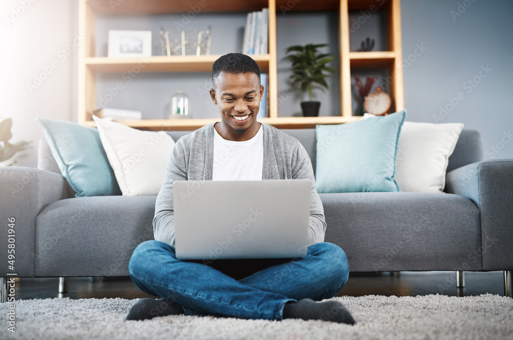 Connecting with an online world. Shot of a happy young man using a laptop while relaxing at home. Connecting with an online world. Shot of a happy young man using a laptop while relaxing at home.