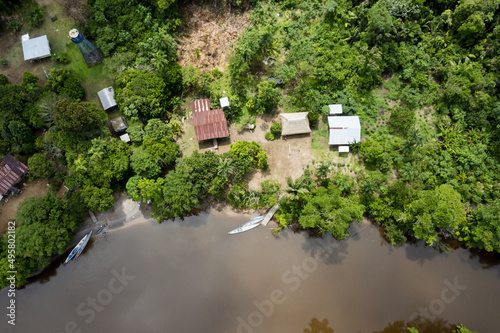 Top view of small houses in an indigenous community in the Amazon rainforest with canoes in the river which are used for transport