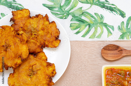 Patacones or fried tostones of green or ripe plantain, crispy, with tomato and onion stew called 