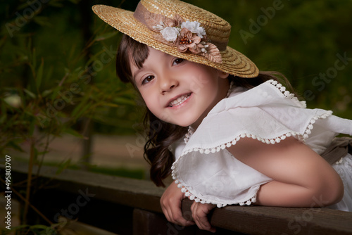 Communion girl posing leaning against a wooden fence in park photo