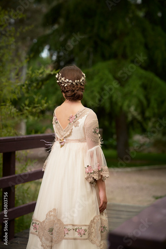 Communion girl posing with her back turned in a park photo