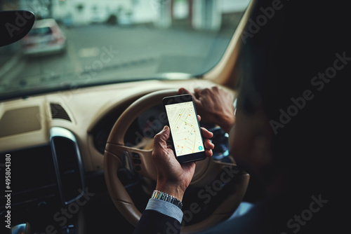 Getting there safely thanks to gps. Cropped shot of a businessman using his phones gps while driving a car. photo