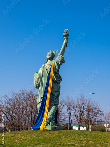 Colmar, France - March 29, 2022: Copy of Statue of Liberty, designed by Frederic Auguste Bartholdi. Statue wrapped with the Ukrainian flag in yellow and blue photo