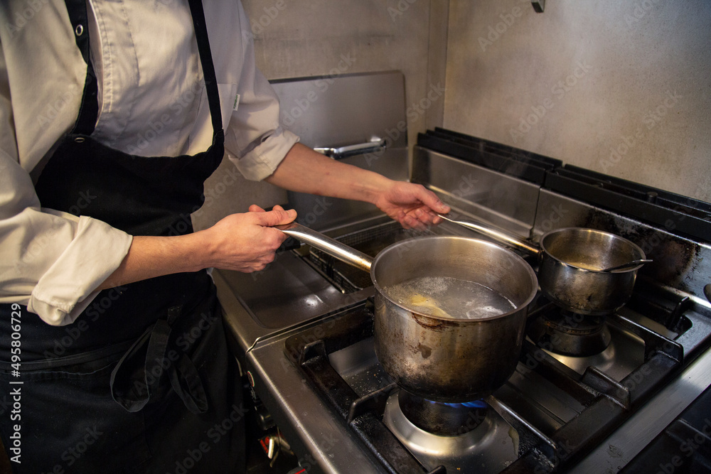 chef manos cocina en olla pasta fresca tortellini en interior cocina restaurante con uniforme blanco y mandil negro chef manos cocina en olla pasta fresca tortellini en interior cocina restaurante con uniforme blanco y mandil negro