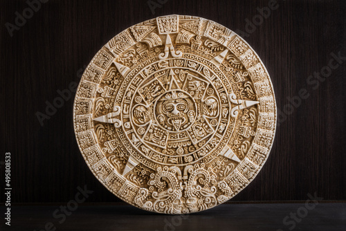 Round engraved stone with Aztec calendar on a wooden background photo