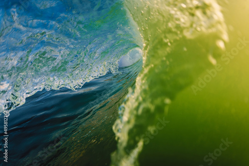 Surfing swell with yellow tones in ocean. Barrel wave with sunset light