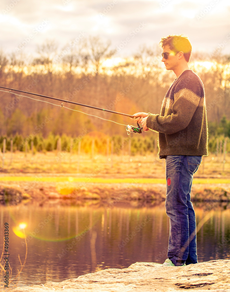 A fisherman standing on the edge of a lake. A fisherman standing on the edge of a lake.