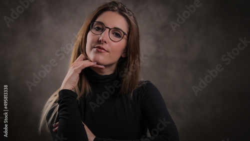 Close-up of a young attractive woman against dark grey background - studio photography