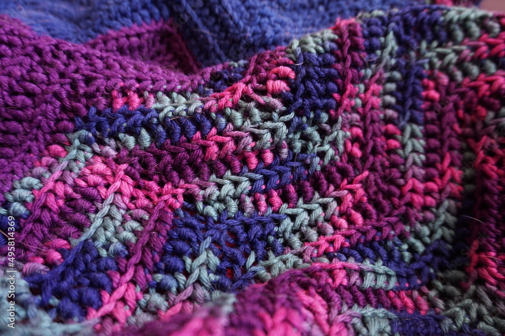 Pink, Mauve, Blue, Green Variegated Crocheted Afghan Blanket as Background