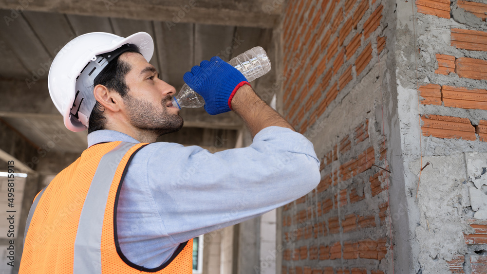 Middle Eastern handsome engineer drinking water to quench thirst. Drinking enough water on hot days.workers are tired from work.Image of a person holding a water bottle and drinking it all. Middle Eastern handsome engineer drinking water to quench thirst. Drinking enough water on hot days.workers are tired from work.Image of a person holding a water bottle and drinking it all.