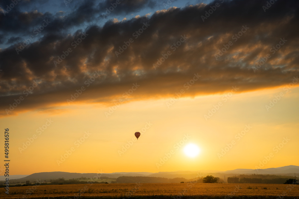 Landscape with hot air balloon at sunset with dramatic clouds