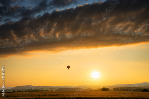 Obraz na płótnie Landscape with hot air balloon at sunset with dramatic clouds w salonie