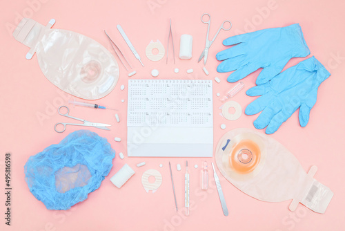 Surgeon's kit for surgery with an annual calendar 2022 and a colostomy bag on a soft pink background. photo