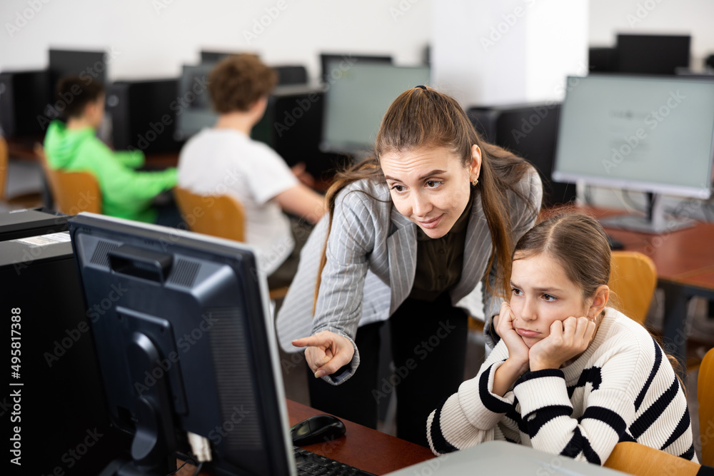 Fototapeta premium Positive woman teacher together with the girl teaches how to work on the computer