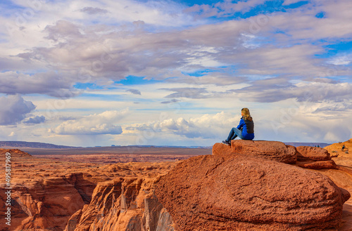 Fotografiet a beautiful girl sitting on the rock and looking at Grand Canyon, Horseshoe bend