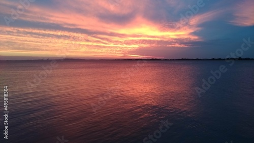 Beautiful red sky in Porto Alegre, Brasil at sunset with some clouds and the view of Atlantic Ocean.