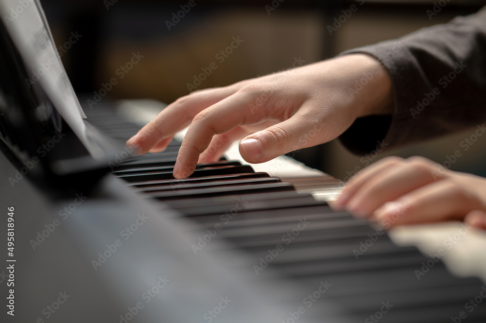 Child's hand presses the piano keys