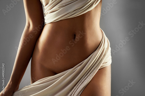 Curves worth showing off. Studio shot of an unrecognizable sexy young woman posing nude with a sarong against a grey background. photo