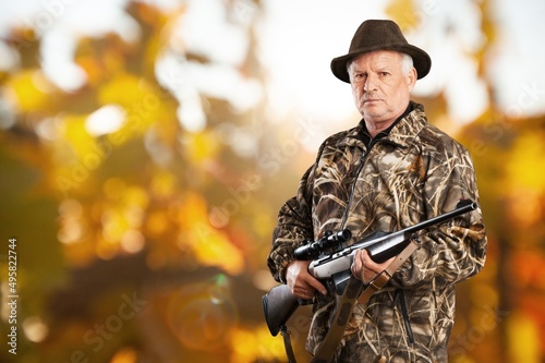 Male hunter in forest clothes holding gun ready to hunt, and walking in forest. Hunting and people concept.