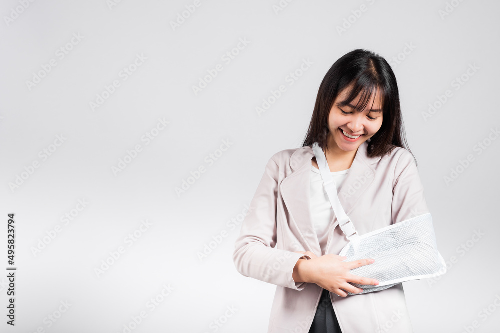Arm broken. Business woman confident smiling broken arm after accident and wear arm splint for treatment, excited happy Asian female sling support hand studio isolated on white background, copy space Arm broken. Business woman confident smiling broken arm after accident and wear arm splint for treatment, excited happy Asian female sling support hand studio isolated on white background, copy space