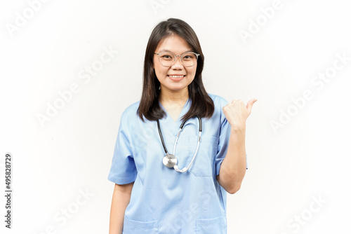 Showing and Pointing Product With Thumb Of Asian Young Doctor Isolated On White Background