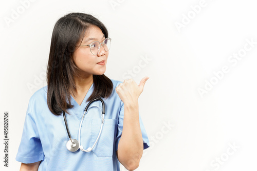 Showing and Pointing Product With Thumb Of Asian Young Doctor Isolated On White Background