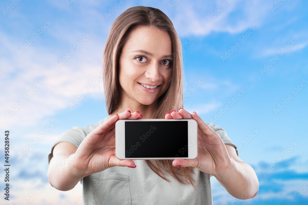 Smiling beautiful woman wearing T-shirt against blue background  Hold mobile phone with blank empty screen