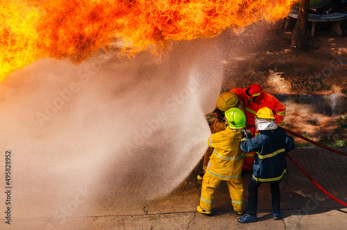 Firefighter training., fireman using water and extinguisher to fighting with fire flame in an emergency situation., under danger situation firemen wearing fire fighter suit for safety.