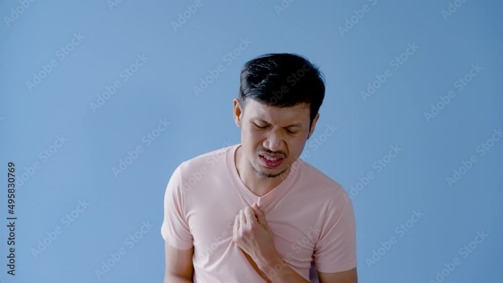 4K 50fps, Asian man mustache,Half of the young man's left hand grabbed his chest and rubbed it back and forth, with a severe pain in his chest.,Isolated indoor studio on blue background. 4K 50fps, Asian man mustache,Half of the young man's left hand grabbed his chest and rubbed it back and forth, with a severe pain in his chest.,Isolated indoor studio on blue background.