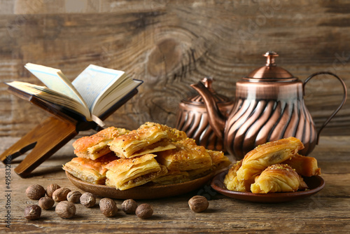 Tasty Turkish baklava and tea with Quran on wooden background