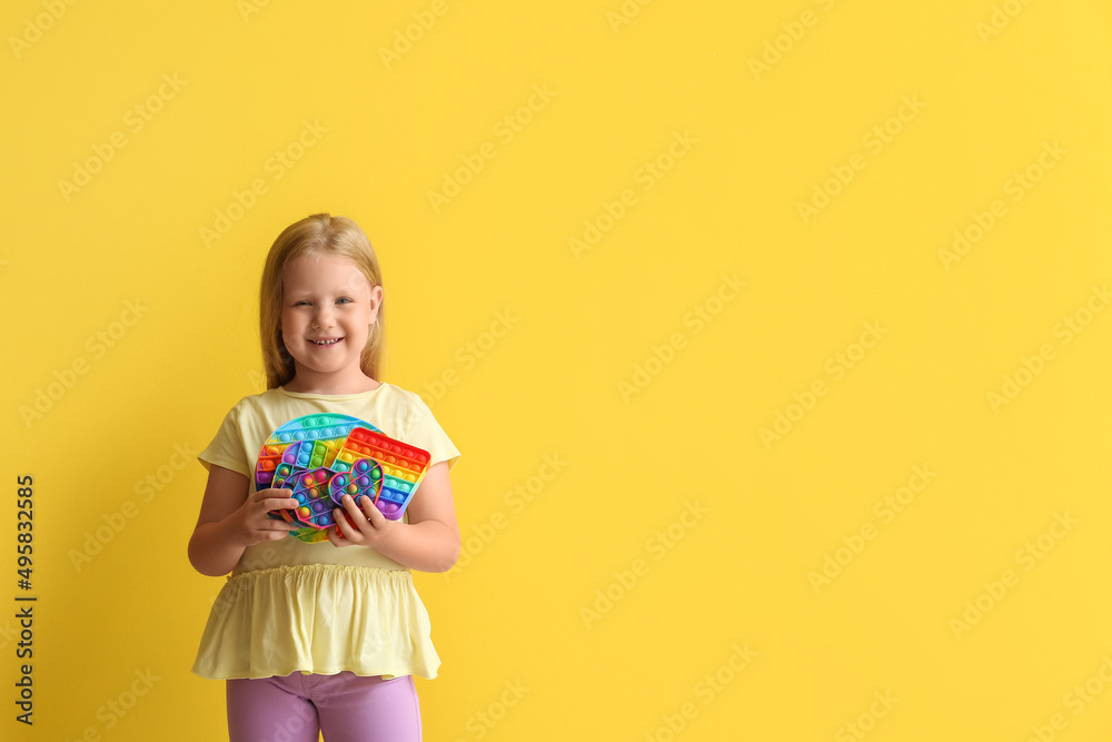 Happy little girl holding pop it fidget toys on color background Happy little girl holding pop it fidget toys on color background