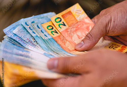 Um homem contando notas do Real Brasileiro - BRL, dinheiro do Brasil. Conceitos de finanças, negócios e economia brasileira. photo