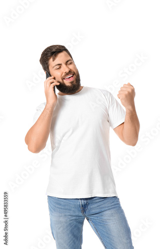 Handsome man in t-shirt talking by mobile phone on white background