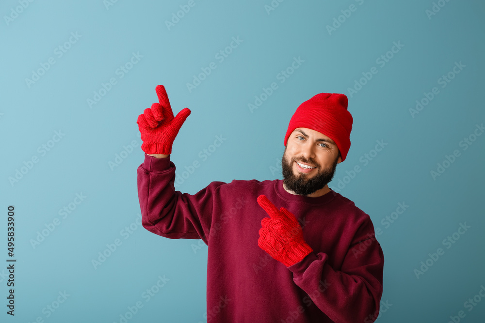 Handsome man in winter clothes pointing at something on color background Handsome man in winter clothes pointing at something on color background
