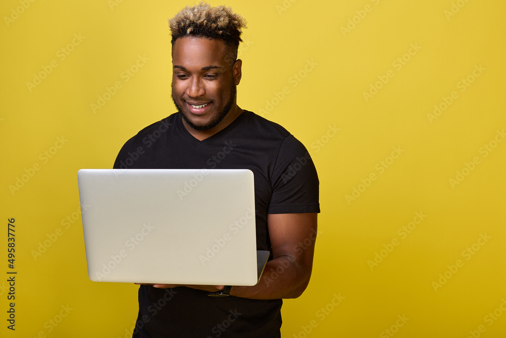 Handsome, muscular guy holds a laptop and reads an email. Smiling black guy communicates in social networks with friends by correspondence using a modern laptop Handsome, muscular guy holds a laptop and reads an email. Smiling black guy communicates in social networks with friends by correspondence using a modern laptop