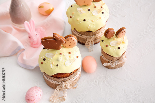 Delicious Easter cakes decorated with cookies and painted eggs on light background © Pixel-Shot