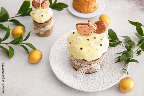 Delicious Easter cakes decorated with cookies and painted eggs on light background © Pixel-Shot