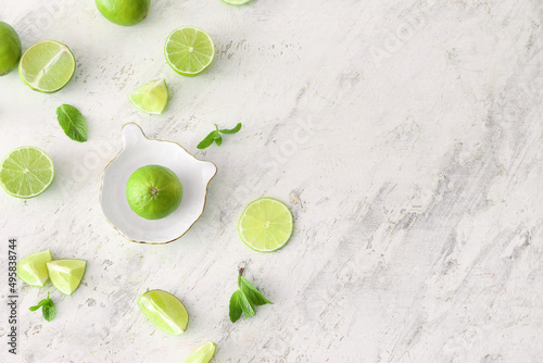 Ceramic juicer and limes on light background