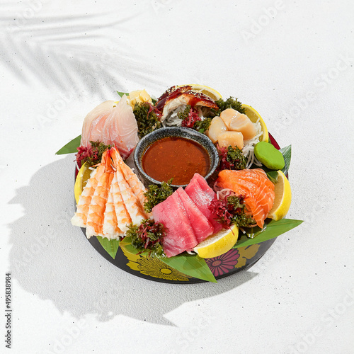 Sashimi set from raw seafood: salmon, tuna, eel, perch, shrimps, sea scallop. Traditional japanesse dish - sashimi on white background. Fresh delicacy on ice with lemon, ginger and sauce.