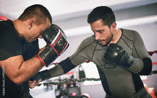 Put your hands up. Shot of two young male boxers facing each other in a training sparing match inside of a boxing ring at a gym during the day.