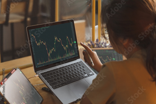 Fotografie Businesswoman, female trader, investor pointing, using laptop, tablet with graph