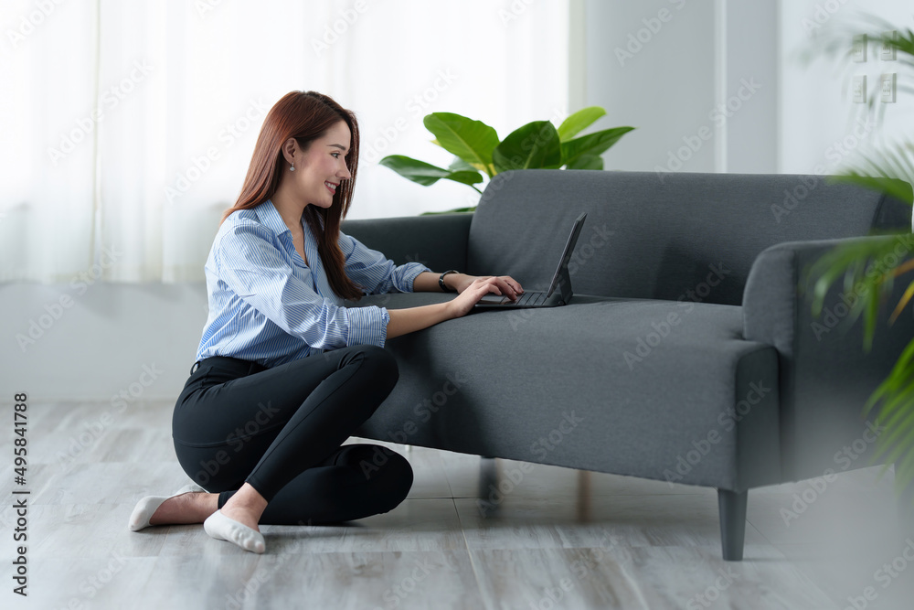 Woman enjoy with content streaming movies or social media application on digital tablet sitting near sofa at home.