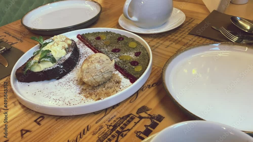 Untouched dessert on the table. Chocolate pear cake with vanilla ice cream decorated with microgreens and halva