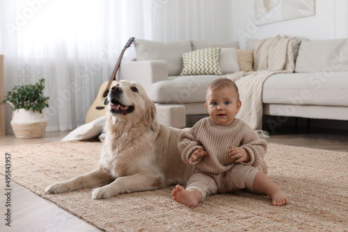 Fototapeta Naklejka Na Ścianę i Meble -  Cute little baby with adorable dog on floor at home