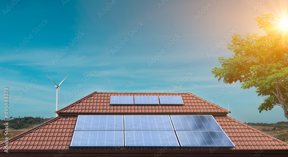 Solar panel on a roof of a house with wind turbines around. Photovoltaic, alternative electricity source. sustainable resources Solar panel on a roof of a house with wind turbines around. Photovoltaic, alternative electricity source. sustainable resources