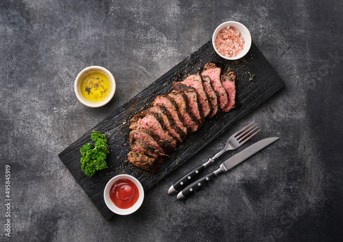 Foto Grilled sliced beef steak on cutting board over grey table