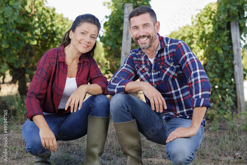 farming couple knelt by vines