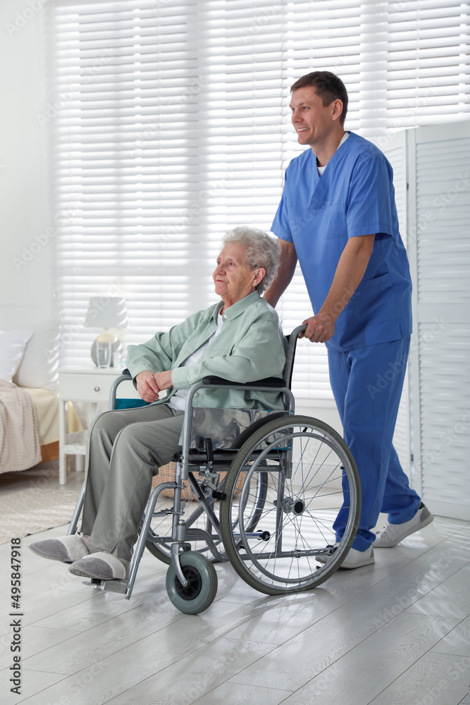 Caregiver assisting senior woman in wheelchair indoors. Home health care service Caregiver assisting senior woman in wheelchair indoors. Home health care service