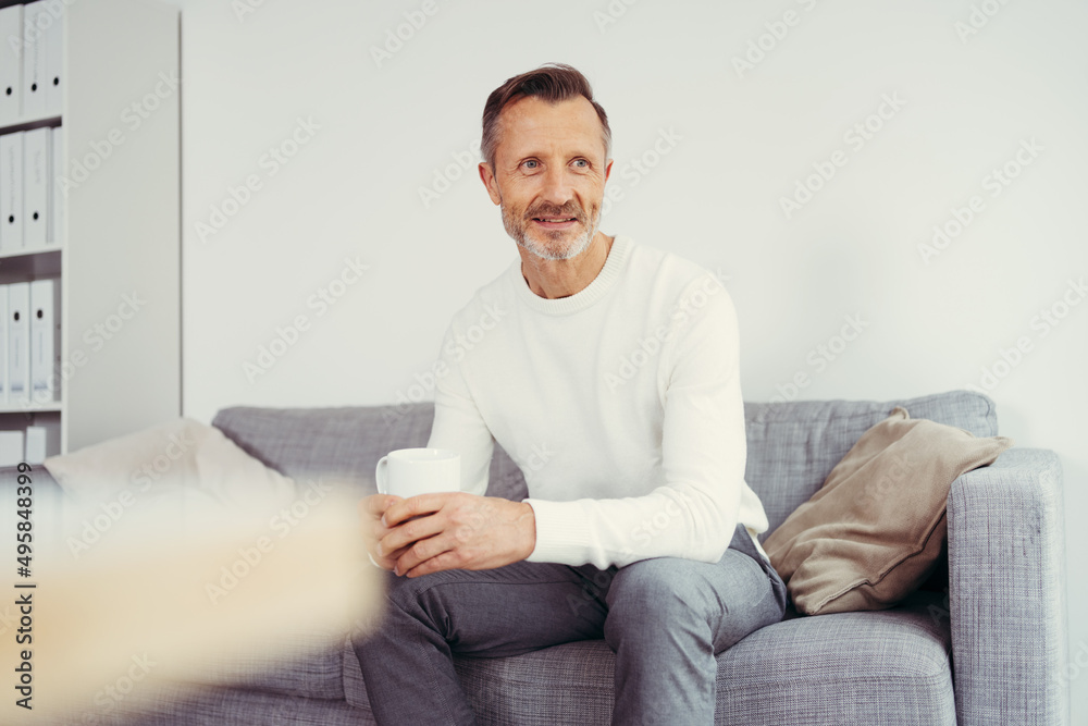 older man sitting at home on sofa and looking to the side