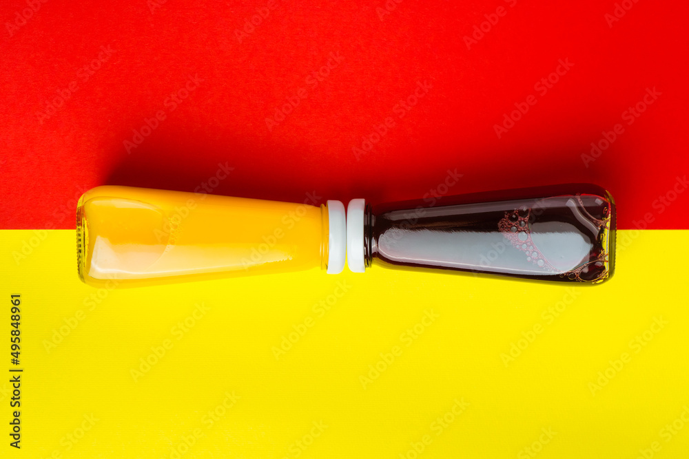 Bottles with yellow and red liquid halthy beverage on yellow and red background. Orange cherry juice Bottles with yellow and red liquid halthy beverage on yellow and red background. Orange cherry juice
